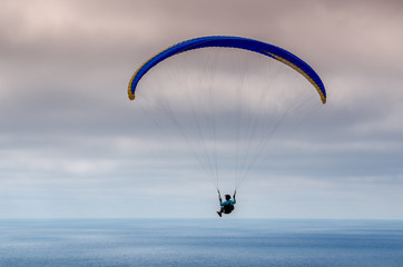 Colorful hang glider/paraglider against the blue sky