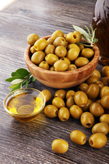 Bottle virgin olive oil and oil in a bowl with some olives