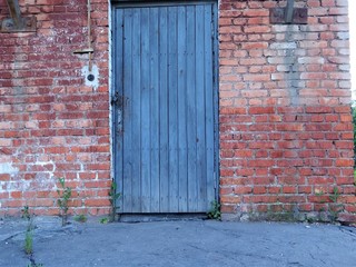 Wooden old painted blue , shabby door in a brick wall.