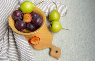  Pears and plums in a plate on a linen tablecloth