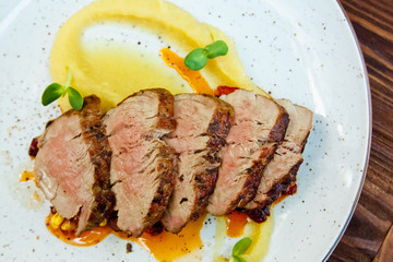 Pork tenderloin with mashed potatoes, their baked apples on white plate with sauce. Food background