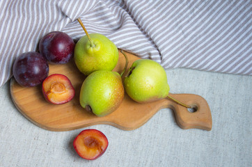 Pears and plums on wood on a linen tablecloth
