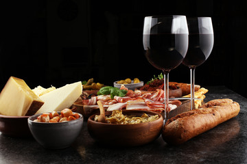 Italian antipasti wine snacks set. Cheese variety, Mediterranean olives, pickles, Prosciutto di Parma, tomatoes, artichokes and wine in glasses