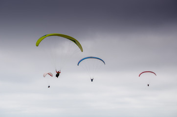 Multiple colorful paraglider flying high in the sky
