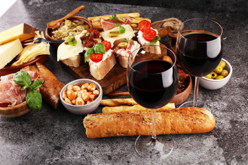 Italian antipasti wine snacks set. Cheese variety, Mediterranean olives, pickles, Prosciutto di Parma, tomatoes, artichokes and wine in glasses