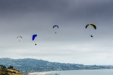 Colorful hang gliders/paraglider flying high over the ocean at Torrey Pines Glider Port, La Jolla, San Diego, California