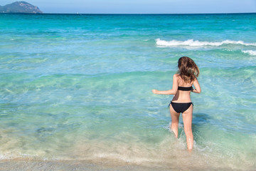 Young woman in bikini with her hand over head enjoying hot summer day on the beautiful Playa de Muro beach, Mallorca, Spain