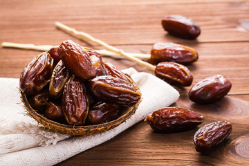 Sweet dried dates fruit in a small bowl on napkin on wooden table