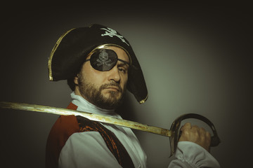 Man with beard dressed like a pirate, with eye patch and steel sword