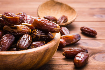 Sweet dried dates fruit in a wooden bowl and on the table.