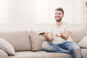 Amused young man wathing tv at home