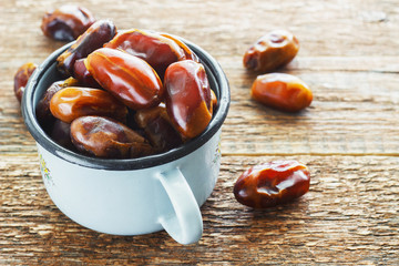 Dates in a blue metal mug on an old wooden background