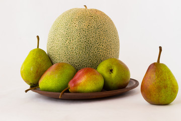 Pears and melon on  ceramic plate. White background