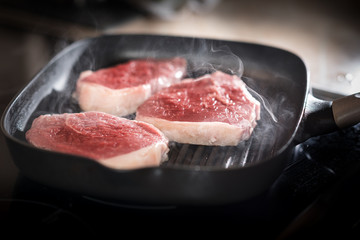 cooking rib eye steak on grill pan.