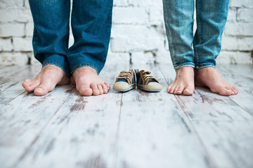 Waiting for the baby. Children's shoes with the feet of parents