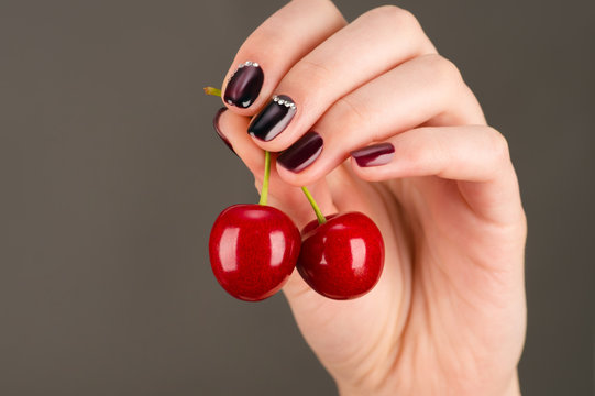 beautiful juicy cherry in female hand with luxurious manicure