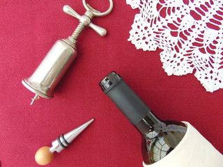 Bottle of red wine with corkscrew on bordeaux red background