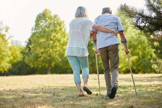 Caregiver Helps Man Walking With Crutches