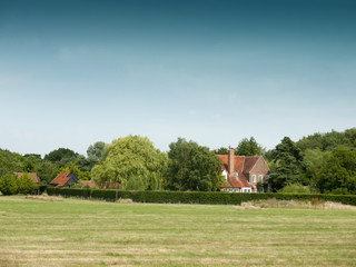 Obraz premium country farm house behind trees and field