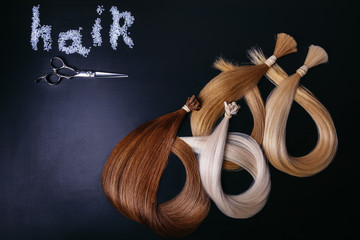 hair extensions of three colors on a dark background. copyspace. top view.