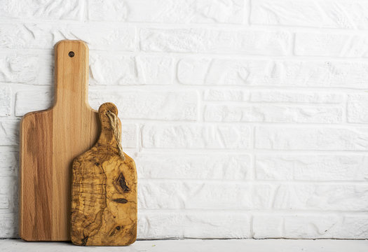 Kitchen tools, olive cutting board on a kitchen shelf against a white brick wall. selective focus