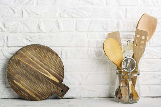 Kitchen tools, olive cutting board on a kitchen shelf against a white brick wall. selective focus