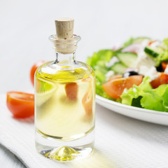 Bottle of olive oil with fresh vegetable Greek salad; closeup