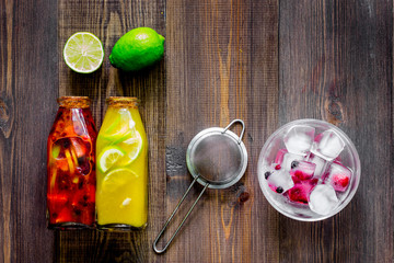 Bottle of fresh lemonade, fruits and ice cubes on wooden background top view copyspace