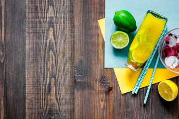 Bottle of fresh lemonade, fruits and ice cubes on wooden background top view copyspace