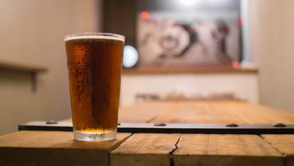 Glass of beer on wooden table in pub background