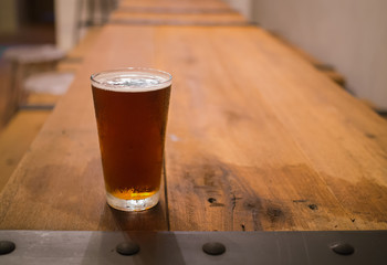 Glass of beer on wooden table in pub background