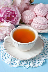 Tea cup, zephyr cookies  and peonies on wooden table.  Wedding or birthday conception