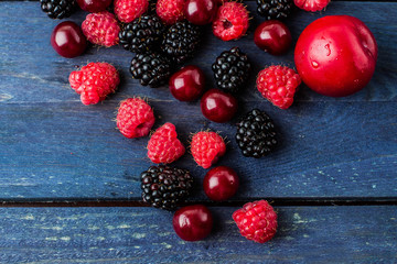 Food Background. Summer fresh berries on blue wooden table background. Copy space. Top view Vegetarian food - raspberry, blackberry and cherry. Rustic style