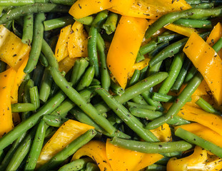 Pods of green beans mixed with pieces of yellow bell pepper.