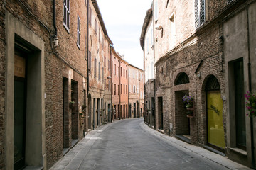 Fototapeta na wymiar Curved street of an ancient medieval Italian village, with wooden doorways and windows. Traveling Italy, Tuscany and Umbria .