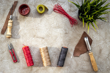 Set of leather craft tools on grey stone background top view copyspace