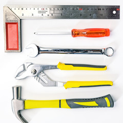 Top view of Working tools,wrench,socket wrench,hammer,screwdriver,plier,electric drill,tape measure,machinist square on white background. flat lay