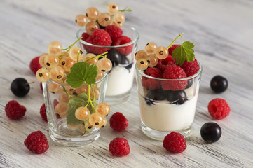 Sour cream in a glass with raspberries and currants. Assorted berries with sour product.