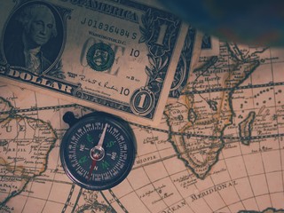 Antique pirate world map and new modern compass concept travel around the world with one dollar money of United States of America, vintage vintage