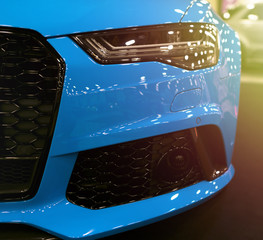 Front view of blue modern luxury sport with soft orange sun light. Car exterior details. Headlight...