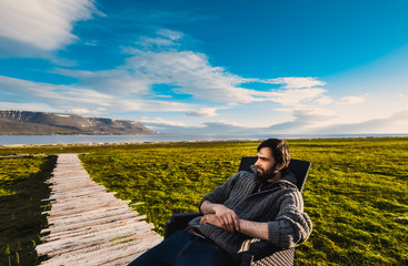 Portrait norway landscape nature of the mountains of Spitsbergen Longyearbyen Svalbard man  in sweater with beard smiling lyifestyle on a polar day  arctic summer in the sunset and blue cloudly sky  