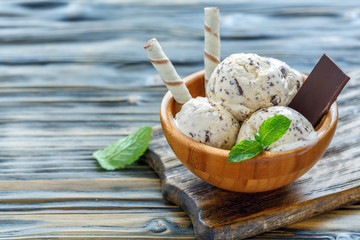 Ice cream with chocolate crumb in a wooden bowl.