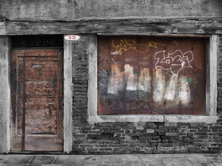 derelict decaying shop building with boarded up window and vandalism