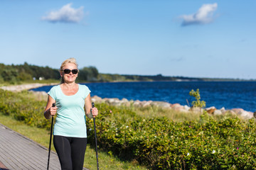 Nordic walking - middle-age woman working out in city park