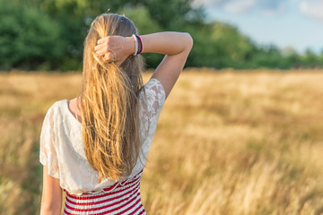 ein junges Mädchen greift von hinten in Ihre Haare in einem Weizenfeld