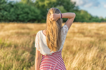 ein junges Mädchen greift von hinten in Ihre Haare in einem Weizenfeld