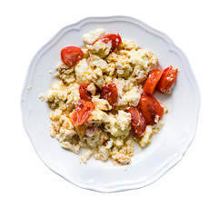 Fried eggs with slices of tomatoes in plate isolated on white