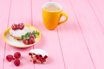 Homemade baked muffin with raspberries, fresh berries, mint on plate and cup of coffee on pink wooden background.