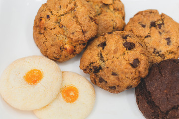 Top view of a plate of oatmeal chocolate, shortbread cookies on a white background