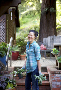 Woman smiling holding plants in her yard